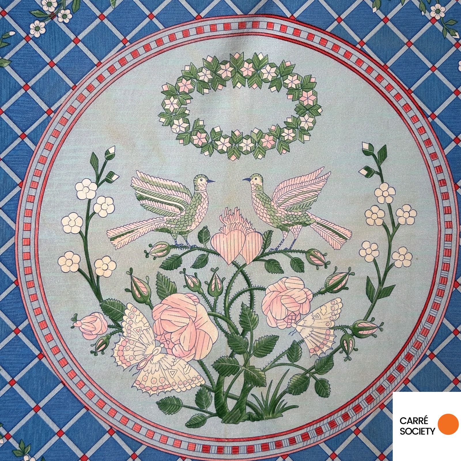 Gros plan sur le médaillon central du carré Hermès Jeux de Paille représentant deux colombes, des roses et une guirlande florale.
