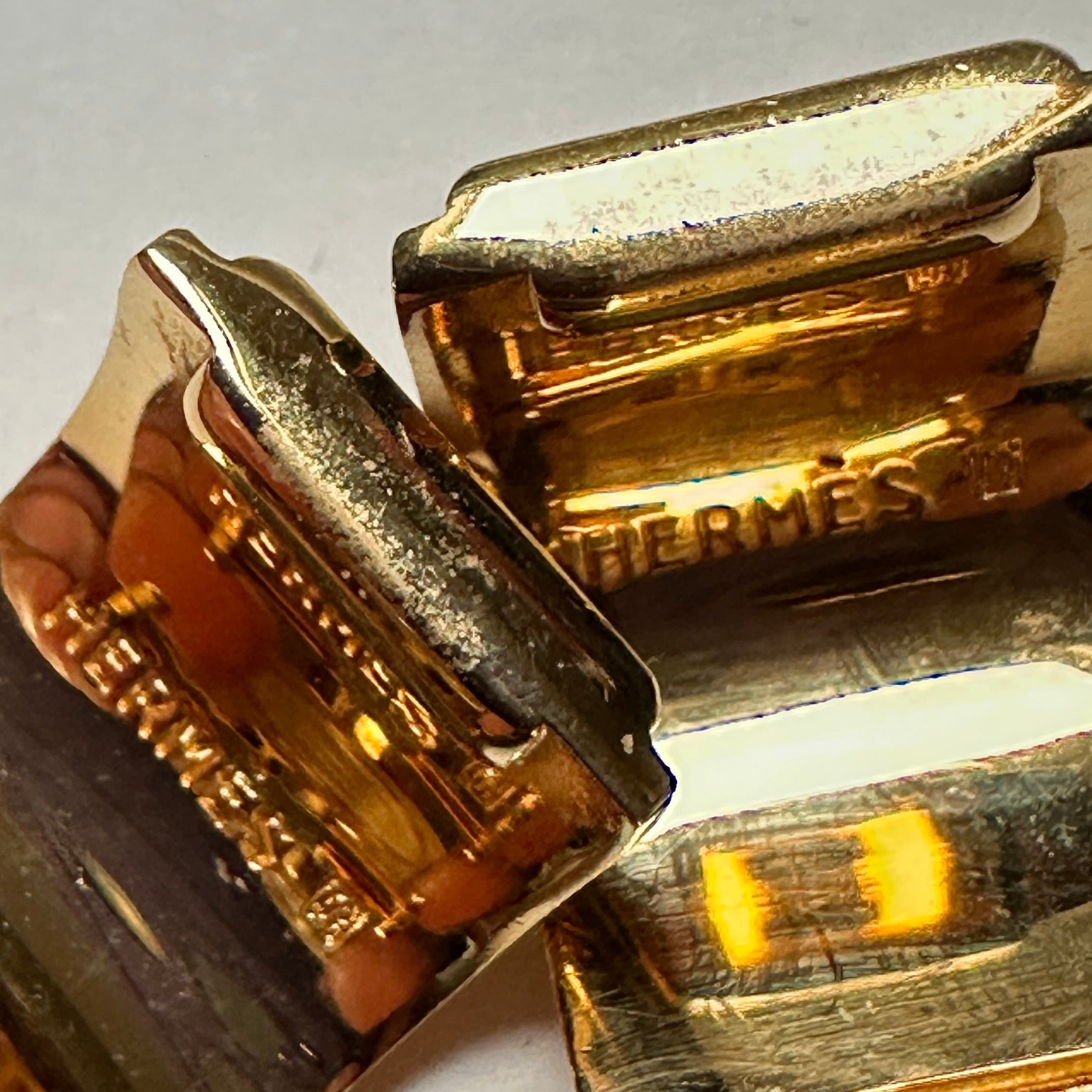 Vue arrière des deux boucles d'oreilles montrant l'état de la dorure et la gravure de la signature HERMÈS PARIS.