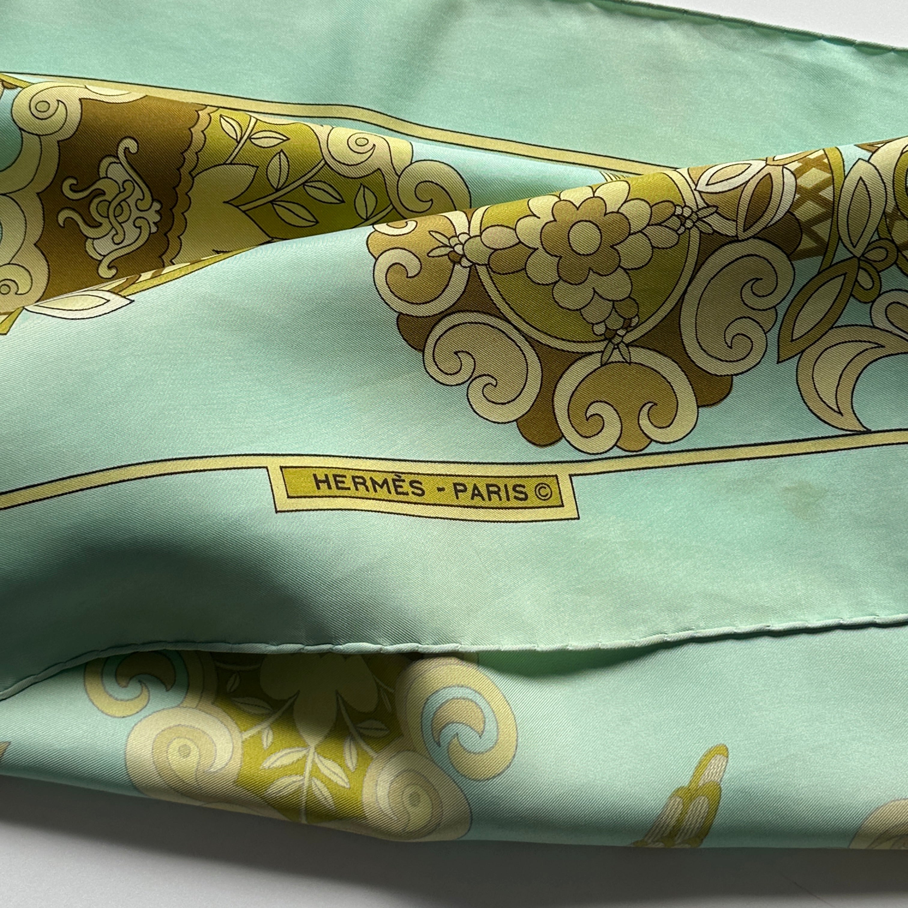 Détail de la bordure inférieure montrant le logo "HERMÈS - PARIS ©" dans un cartouche rectangulaire jaune.