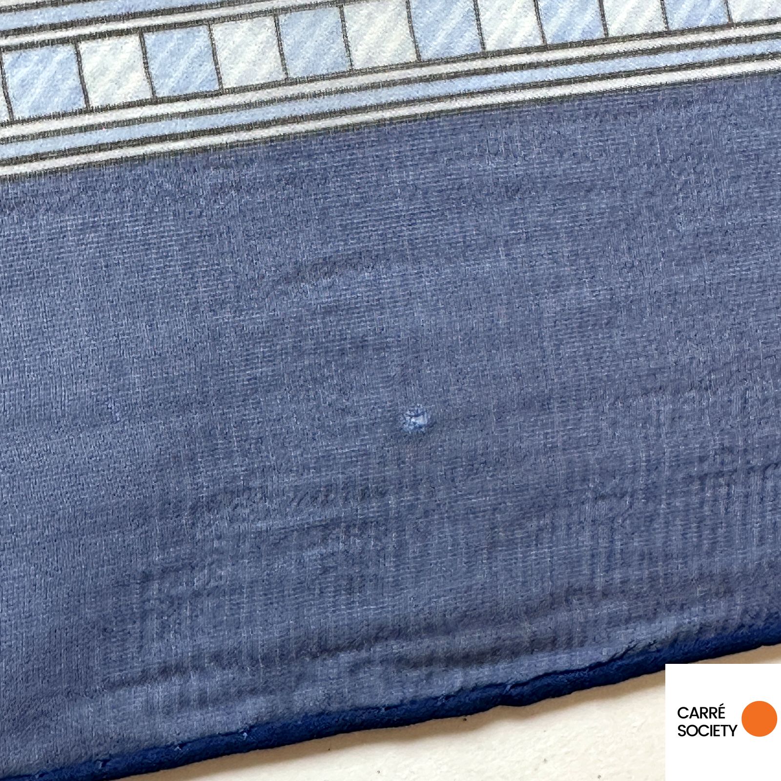 Détail d'un tout petit trou et du bord roulotté main bleu du foulard Hermès Jeux de Paille en voile de soie